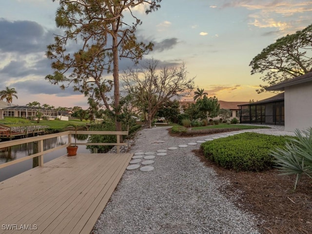 view of yard featuring a deck with water view and a sunroom