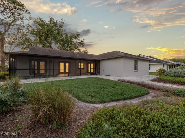 back of house with stucco siding and a lawn