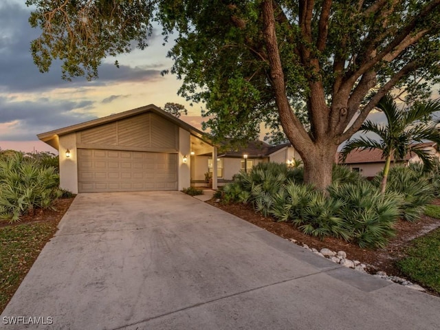 mid-century home featuring an attached garage, driveway, and stucco siding