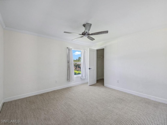 empty room with baseboards, light carpet, ornamental molding, and a ceiling fan