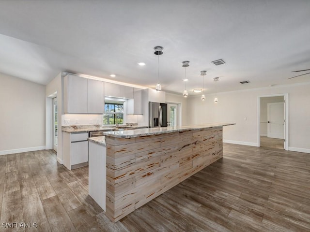 kitchen featuring light stone counters, wood finished floors, visible vents, a kitchen island, and appliances with stainless steel finishes