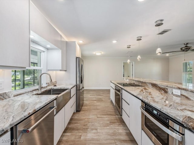 kitchen featuring modern cabinets, pendant lighting, a sink, appliances with stainless steel finishes, and white cabinets