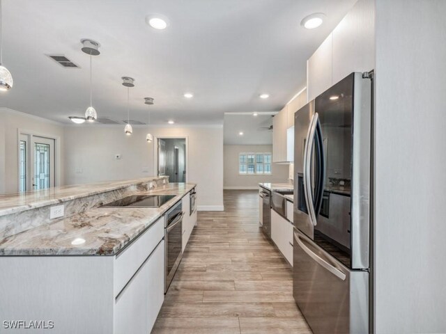 kitchen with visible vents, modern cabinets, white cabinetry, appliances with stainless steel finishes, and hanging light fixtures