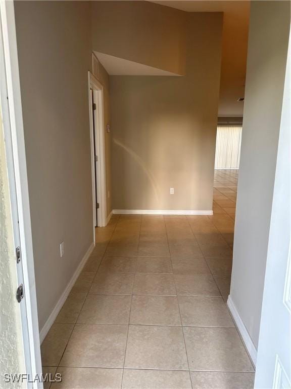 empty room featuring light tile patterned floors and baseboards