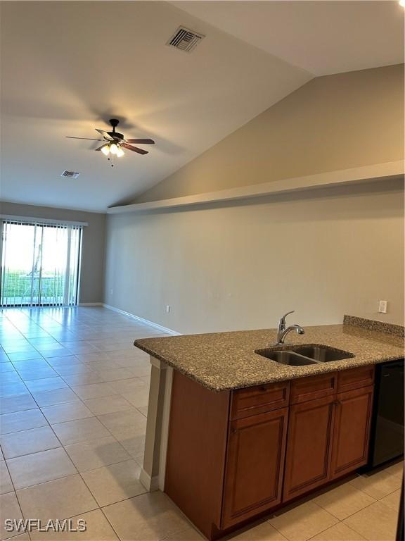 kitchen featuring visible vents, dark stone countertops, lofted ceiling, and a sink