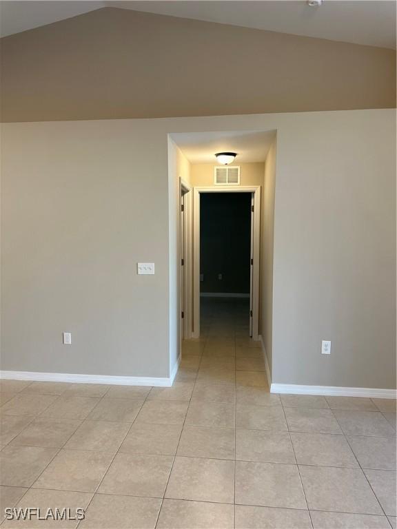 hall with lofted ceiling, light tile patterned flooring, baseboards, and visible vents