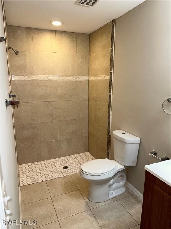 full bathroom with tile patterned flooring, tiled shower, toilet, and vanity