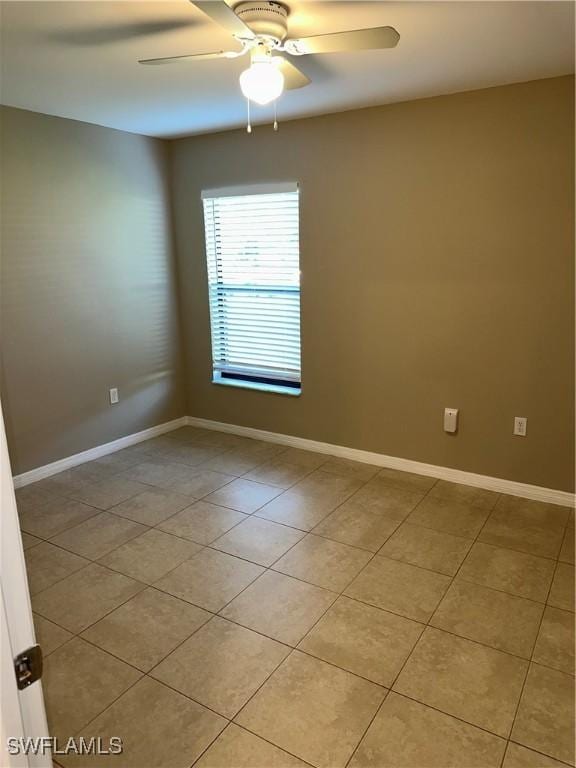 empty room with light tile patterned flooring, baseboards, and ceiling fan