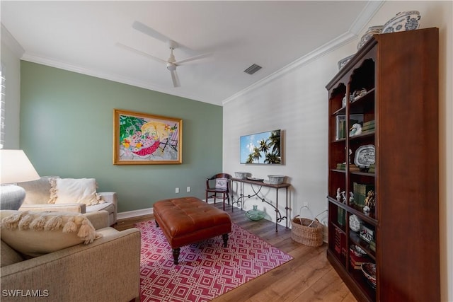 living area featuring crown molding, visible vents, ceiling fan, and wood finished floors