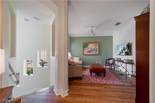 sitting room featuring crown molding, visible vents, ceiling fan, wood finished floors, and baseboards