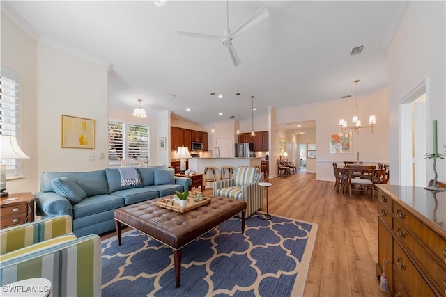 living area featuring recessed lighting, ceiling fan with notable chandelier, visible vents, light wood finished floors, and crown molding