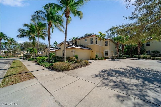 view of front facade with a garage, a residential view, concrete driveway, and stucco siding