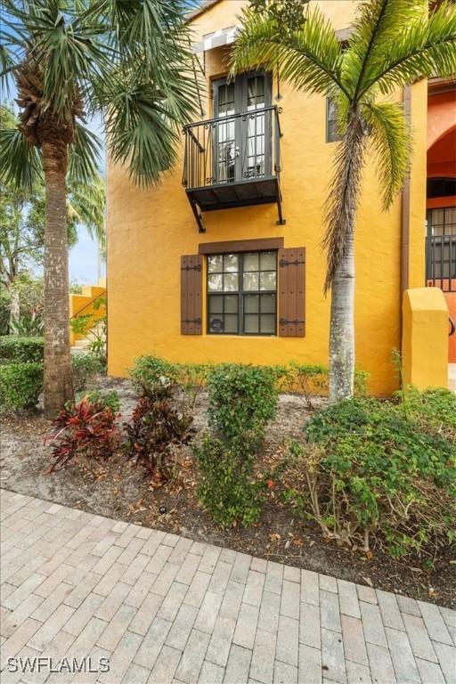 view of side of home featuring a balcony and stucco siding