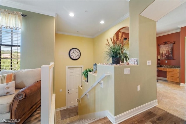 stairs with crown molding, built in desk, and wood finished floors