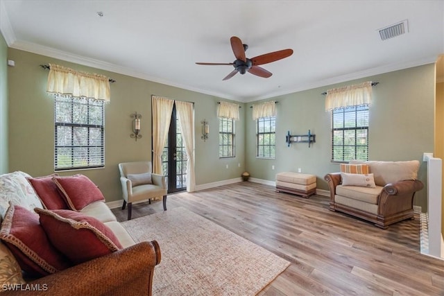 sitting room with baseboards, light wood-style flooring, visible vents, and crown molding