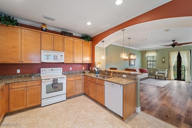 kitchen featuring pendant lighting, open floor plan, a sink, white appliances, and a peninsula