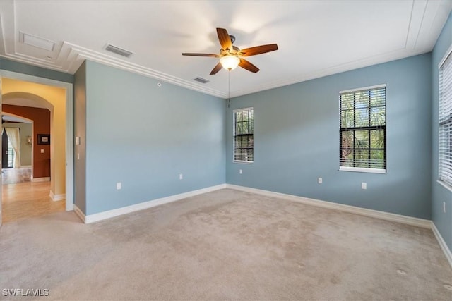 empty room with arched walkways, ceiling fan, light colored carpet, visible vents, and baseboards