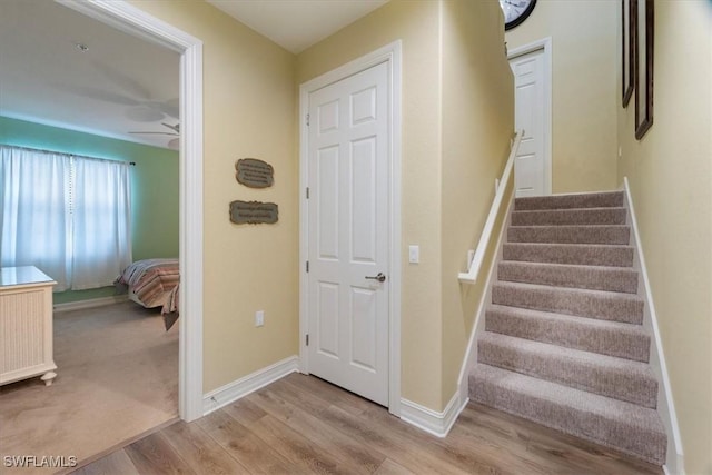 staircase with ceiling fan, wood finished floors, and baseboards