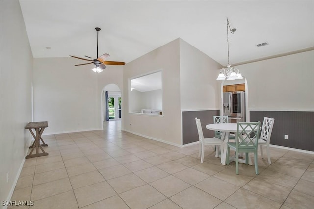 unfurnished dining area featuring visible vents, arched walkways, ceiling fan with notable chandelier, vaulted ceiling, and light tile patterned flooring