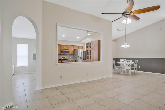 interior space with light tile patterned floors, baseboards, arched walkways, and ceiling fan with notable chandelier