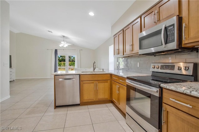 kitchen featuring light tile patterned floors, decorative backsplash, a peninsula, stainless steel appliances, and a sink