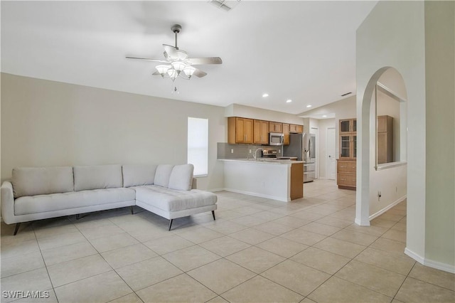 unfurnished living room featuring light tile patterned floors, ceiling fan, arched walkways, recessed lighting, and baseboards