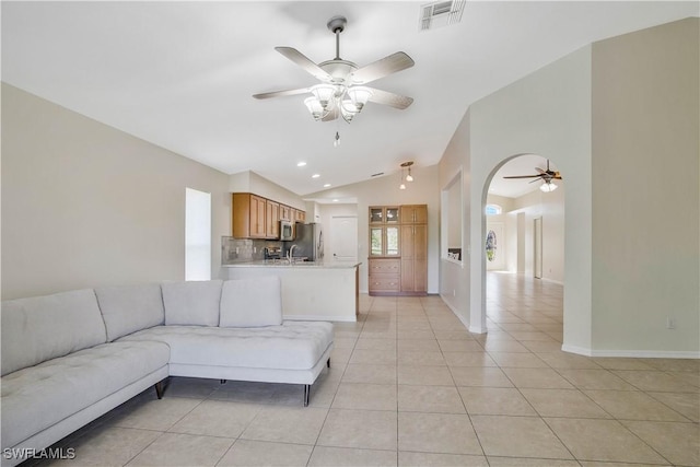 unfurnished living room featuring light tile patterned floors, visible vents, vaulted ceiling, ceiling fan, and baseboards