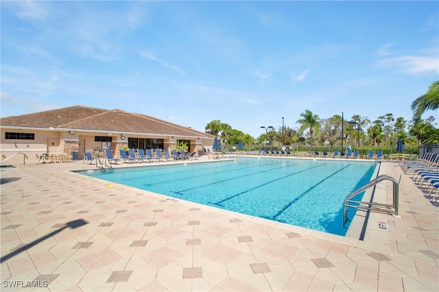 community pool with a patio area and fence