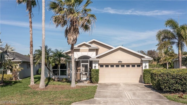 view of front of property with a garage, driveway, a front yard, and stucco siding