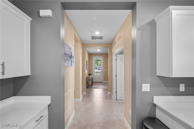 hallway featuring visible vents, baseboards, and light tile patterned floors