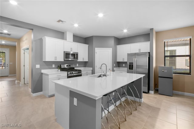 kitchen featuring a spacious island, light countertops, appliances with stainless steel finishes, a sink, and a kitchen breakfast bar