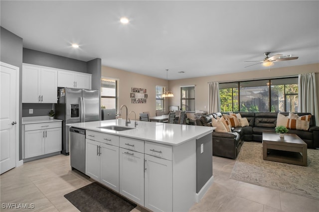 kitchen featuring white cabinets, open floor plan, stainless steel appliances, light countertops, and a sink