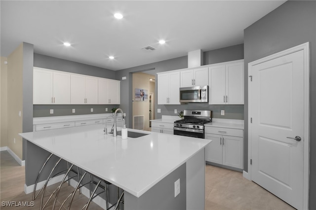 kitchen featuring a center island with sink, light countertops, visible vents, appliances with stainless steel finishes, and a sink