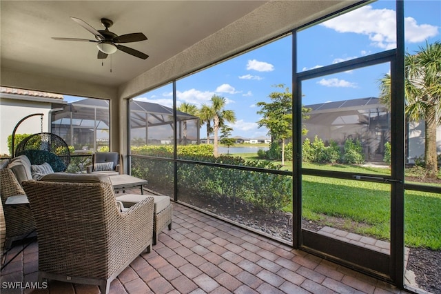 sunroom / solarium featuring a water view, a healthy amount of sunlight, and a ceiling fan