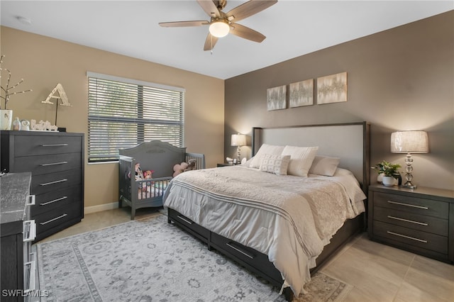 bedroom with light tile patterned floors, a ceiling fan, and baseboards