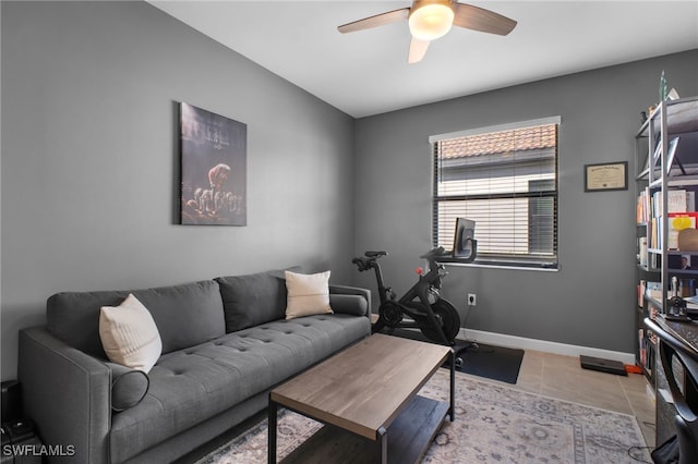 living area with a ceiling fan, tile patterned flooring, and baseboards