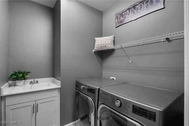 washroom featuring a sink, washing machine and clothes dryer, and cabinet space