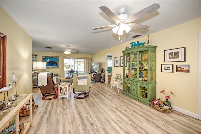 living area featuring light wood finished floors, visible vents, and baseboards