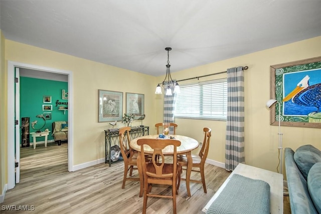 dining space with baseboards, an inviting chandelier, and light wood-style floors