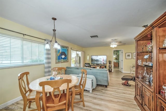 dining space featuring light wood finished floors, ceiling fan, visible vents, and baseboards