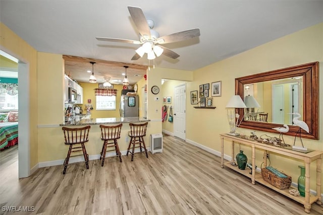 kitchen with pendant lighting, light countertops, appliances with stainless steel finishes, a peninsula, and a kitchen breakfast bar