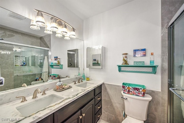 full bath featuring toilet, a shower stall, tile walls, and a sink