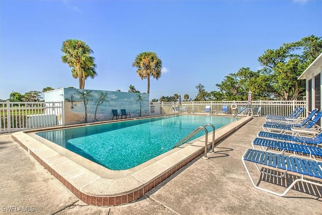 community pool with a patio area and fence