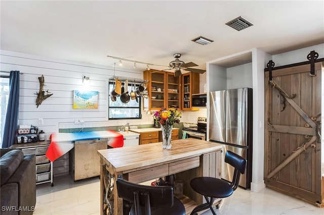 16221 Buccaneer St, Bokeelia, FL 33922 - kitchen with decorative backsplash, visible vents, wood counters, stainless steel appliances, and a barn door