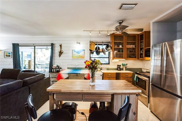 16221 Buccaneer St, Bokeelia, FL 33922 - kitchen featuring ceiling fan, stainless steel appliances, glass insert cabinets, open floor plan, and brown cabinetry