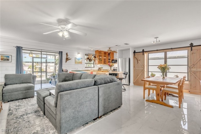 16221 Buccaneer St, Bokeelia, FL 33922 - living room with a barn door, ceiling fan, wood walls, and marble finish floor