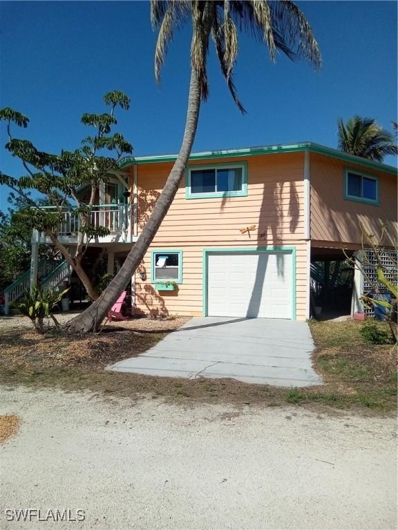 view of front of property featuring a garage, stairs, and concrete driveway