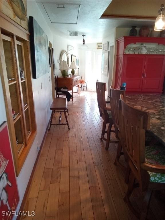 hall featuring wood-type flooring, visible vents, and attic access