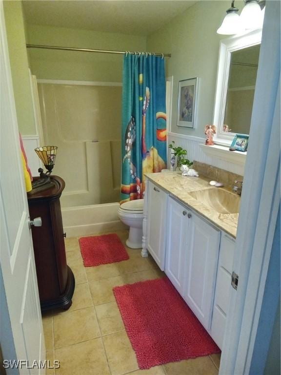 full bathroom featuring a wainscoted wall, toilet, shower / bath combo, vanity, and tile patterned flooring