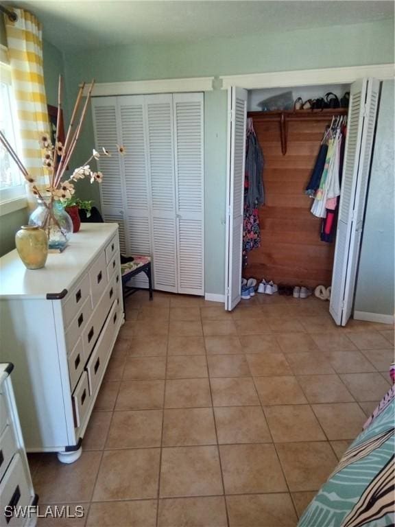 bedroom with two closets, baseboards, and light tile patterned floors